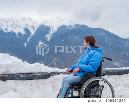 Caucasian woman in a wheelchair travels in the mountains in winter. 106313886