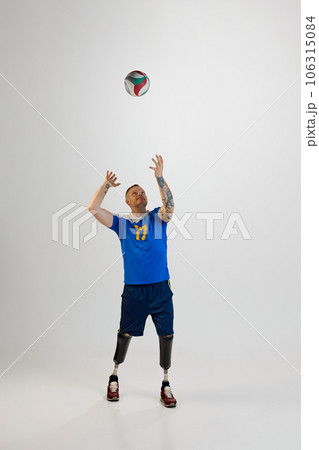 Attractive young man with prosthetic leg disability standing catching volleyball ball. Inclusive sport for people with disabilities. Attractive young man with prosthetic leg disability standing catching volleyball ball. Inclusive sport for people with disabilities. 106315084