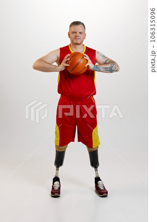 Attractive man with prosthetic leg disability standing holding orange basketball ball. Inclusive sport for people with disabilities. Attractive man with prosthetic leg disability standing holding orange basketball ball. Inclusive sport for people with disabilities. 106315096
