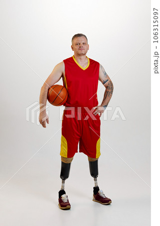 Attractive man amputee with prosthetic leg disability standing holding orange basketball ball. Inclusive sport for people with disabilities. Attractive man amputee with prosthetic leg disability standing holding orange basketball ball. Inclusive sport for people with disabilities. 106315097