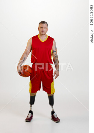 Attractive young man amputee with prosthetic leg disability standing holding orange basketball ball. Inclusive sport for people with disabilities. Attractive young man amputee with prosthetic leg disability standing holding orange basketball ball. Inclusive sport for people with disabilities. 106315098
