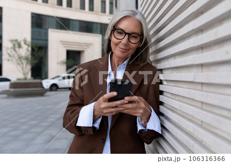 60 year old Caucasian business lady leader dressed in a brown stylish suit walks around the city 60 year old Caucasian business lady leader dressed in a brown stylish suit walks around the city 106316366
