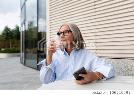 successful free gray-haired business grandmother dressed in a stylish shirt is waiting for a meeting successful free gray-haired business grandmother dressed in a stylish shirt is waiting for a meeting 106316398