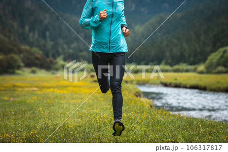 Woman trail runner cross country running in high altitude grassland 106317817