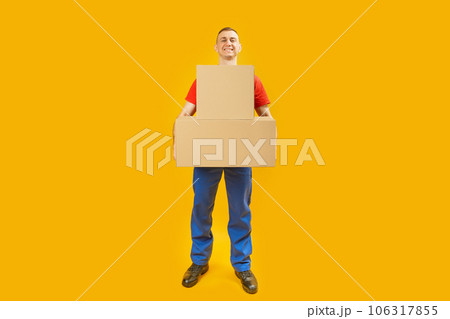 Full-length portrait of young man with large cardboard boxes on yellow background. Copy space, mock up. Full-length portrait of young man with large cardboard boxes on yellow background. Copy space, mock up. 106317855