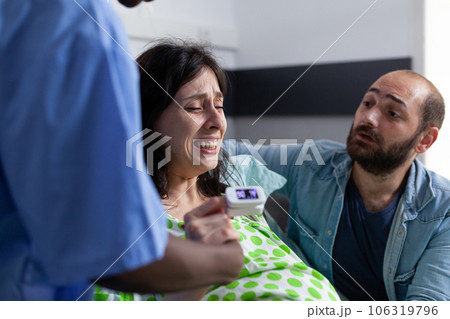 Pregnant woman holding hand of nurse and husband in hospital ward, having painful contractions. Patient with pregnancy getting into labor having medical assistance at healthcare facility. Close up Pregnant woman holding hand of nurse and husband in hospital ward, having painful contractions. Patient with pregnancy getting into labor having medical assistance at healthcare facility. Close up 106319796