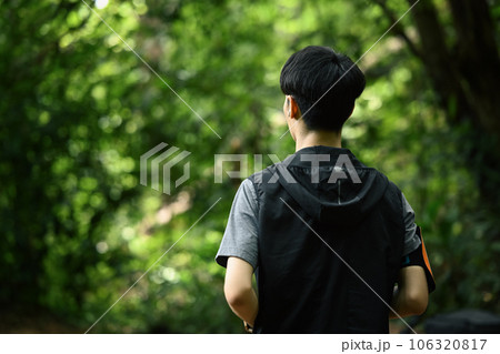 Back view of male trail running through a green forest. Sports motivation, adventure, healthy lifestyle 106320817