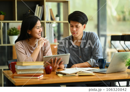 Smiling male and female students discussing homework, brainstorming on common studying project in library Smiling male and female students discussing homework, brainstorming on common studying project in library 106320842