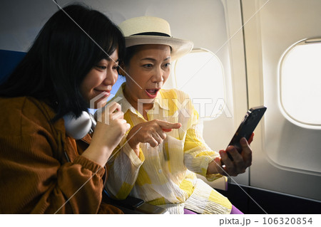 Happy retried woman and daughter sitting in passenger airplane and taking picture, waiting for airplane landing 106320854