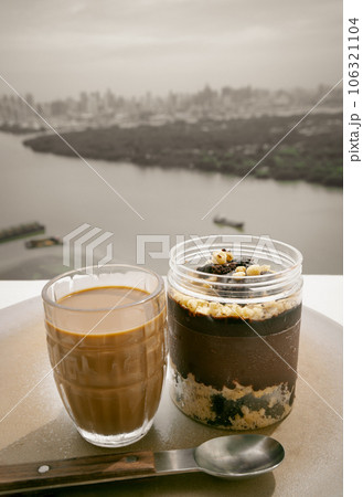 Good morning with Coffee in glass cup and Crumble dark chocolate brownie served and served with spoon with river view. Good morning with Coffee in glass cup and Crumble dark chocolate brownie served and served with spoon with river view. 106321104