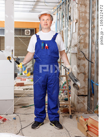 Professional builder handyman working with angle drive grinder indoors 106322472