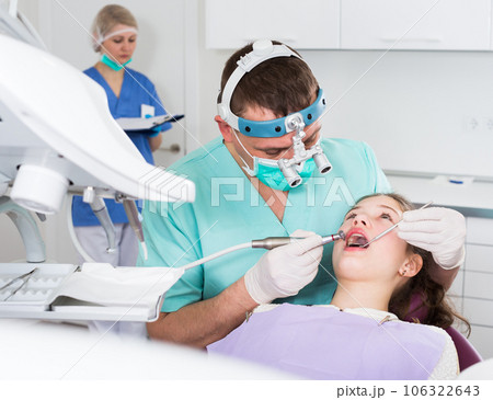 Male dentist performing treatment to girl 106322643