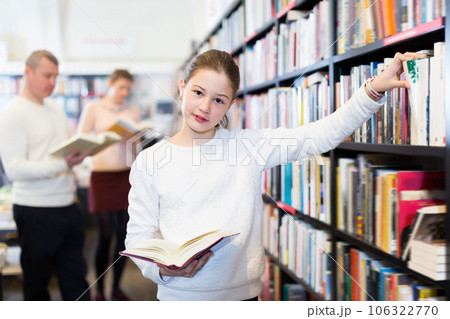 Girl looking for interesting books on rack Girl looking for interesting books on rack 106322770