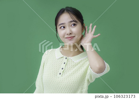グリーンバックの耳に手を当てる若い女性 106323173