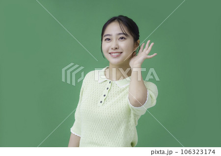 グリーンバックの耳に手を当てる若い女性 106323174