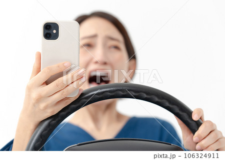 スマホを見ながら驚く女性ドライバー スマホを見ながら驚く女性ドライバー 106324911