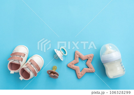 Flat lay of infant items on serene blue, top perspective offering spaciousness Flat lay of infant items on serene blue, top perspective offering spaciousness 106328299