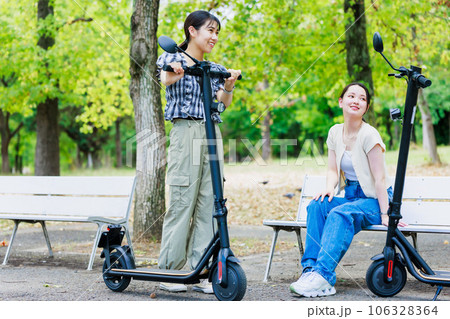 友達と電動キックボードに乗る女子大生 106328364