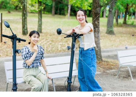 友達と電動キックボードに乗る女子大生 106328365