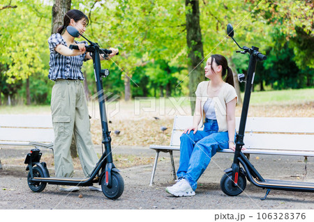 友達と電動キックボードに乗る女子大生 106328376