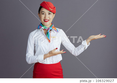 smiling air hostess asian woman welcoming isolated on gray smiling air hostess asian woman welcoming isolated on gray 106329027