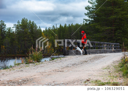 Man walking with dog in nature looking at Autumn lake and forest Man walking with dog in nature looking at Autumn lake and forest 106329051