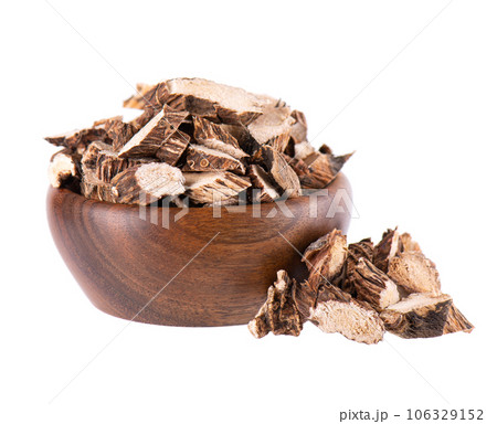 Calamus root in wooden bowl, isolated on white background. Sweet flag, sway or muskrat root. Dry root of Acorus calamus. 106329152