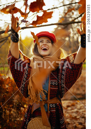 smiling young woman in red hat throwing autumn leafs smiling young woman in red hat throwing autumn leafs 106329385