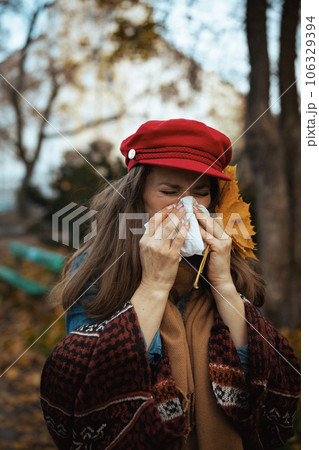 modern woman in red hat blowing nose 106329394