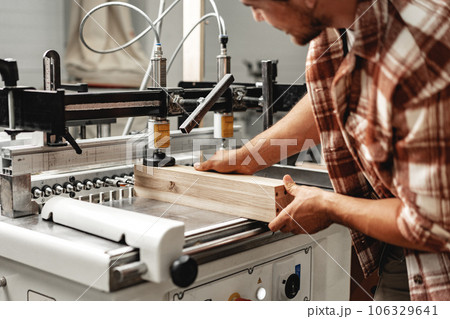 Young carpenter operating machine for wood processing at a furniture factory Young carpenter operating machine for wood processing at a furniture factory 106329641