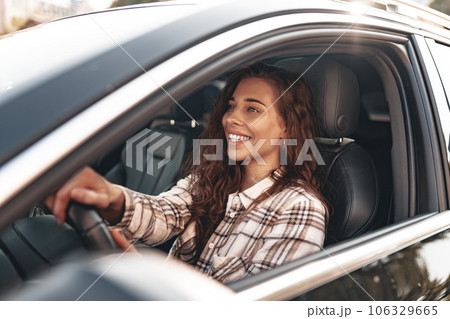 Young smiling woman driving a car in the city 106329665