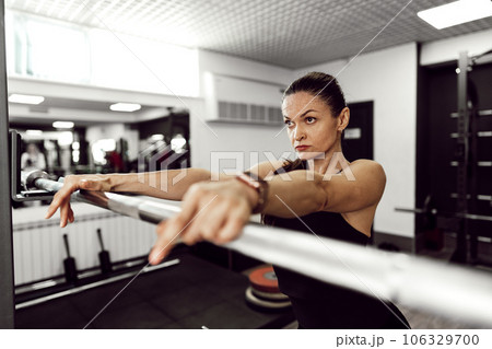 Fit woman doing squats with barbell in a gym 106329700
