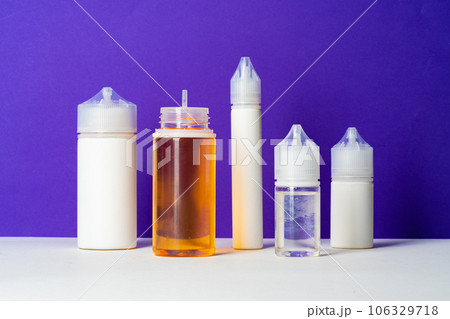 Electronic cigarettes liquid bottles on purple background 106329718
