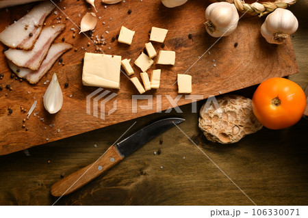 still life of food in a rural style on a dark wood background, sliced lard and garlic, cheese and onion, concept of fresh vegetables and healthy food still life of food in a rural style on a dark wood background, sliced lard and garlic, cheese and onion, concept of fresh vegetables and healthy food 106330071