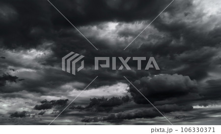 dark dramatic sky with black stormy clouds before rain or snow as abstract background, extreme weather, the sun shines through the clouds, high contrast photo 106330371