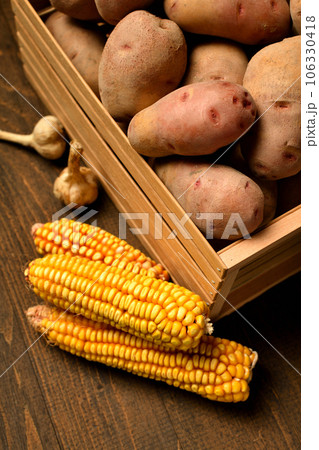 wooden box full of potatoes, garlic bulbs and corn cobs on dark wooden background wooden box full of potatoes, garlic bulbs and corn cobs on dark wooden background 106330418