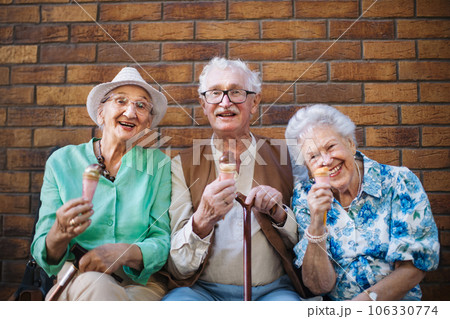 Portrait of three senior friends in the city, eating ice cream on a hot summer day. 106330774