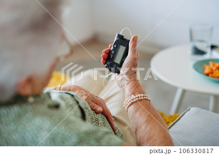 Close up of diabetic senior patient checking her blood sugar level on insulin pump. 106330817