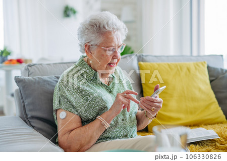 Senior diabetic woman checking her glucose data on smartphone. 106330826