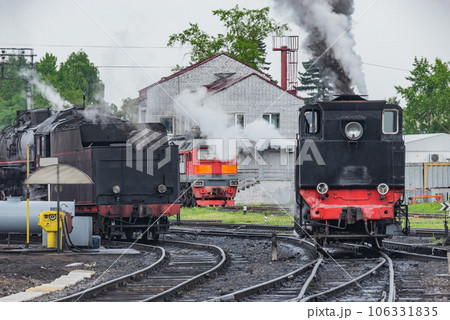 Retro steam locomotives stand near depot. Retro steam locomotives stand near depot. 106331835