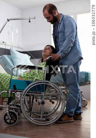 Husband taking pregnant woman in wheelchair to maternity room, preparing for baby delivery in hospital ward. Young couple getting ready for childbirth, discussing parenthood. Birth concept Husband taking pregnant woman in wheelchair to maternity room, preparing for baby delivery in hospital ward. Young couple getting ready for childbirth, discussing parenthood. Birth concept 106332779