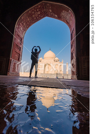 tourist standing in front entrance gate of Taj Mahal indian palace. Islam architecture. Door to the mosque  106334765