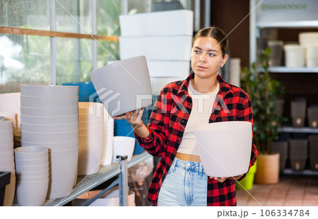 Portrait of woman choosing pots for flowers and trees in market 106334784