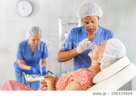 Woman applying rejuvenating treatments by male doctor. Woman applying rejuvenating treatments by male doctor. 106334804