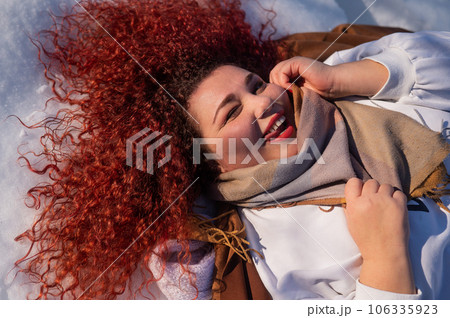 Top view of a fat red-haired woman lying on the snow. Top view of a fat red-haired woman lying on the snow. 106335923