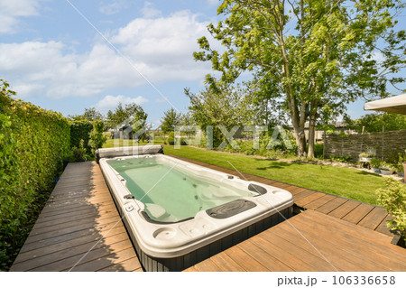 a hot tub on a wooden deck in the backyard with green trees and bushes surrounding it is clear blue sky a hot tub on a wooden deck in the backyard with green trees and bushes surrounding it is clear blue sky 106336658