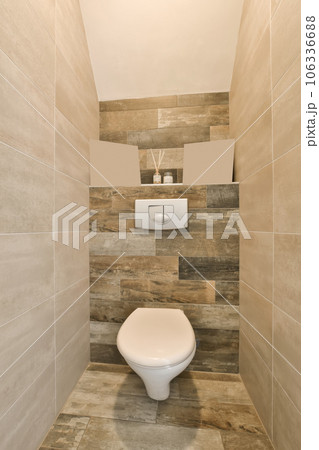a white toilet in a bathroom with wood tiles on the walls and flooring around the toilet is also tiled a white toilet in a bathroom with wood tiles on the walls and flooring around the toilet is also tiled 106336688