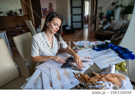 Caucasian woman draws underwear sketches. The fashion designer is holding a lacy bra. 106338098