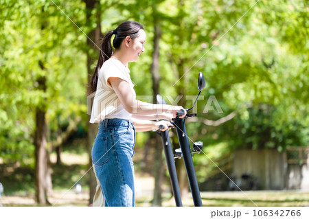 爽やかな陽射しと緑の中を電動キックボードで爽やかに走る若くてかわいい女性|電動キックボードイメージ 爽やかな陽射しと緑の中を電動キックボードで爽やかに走る若くてかわいい女性|電動キックボードイメージ 106342766