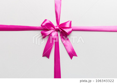 Top view of purple ribbon rolled and pink bow isolated on colored background. Flat lay with copy space 106343322
